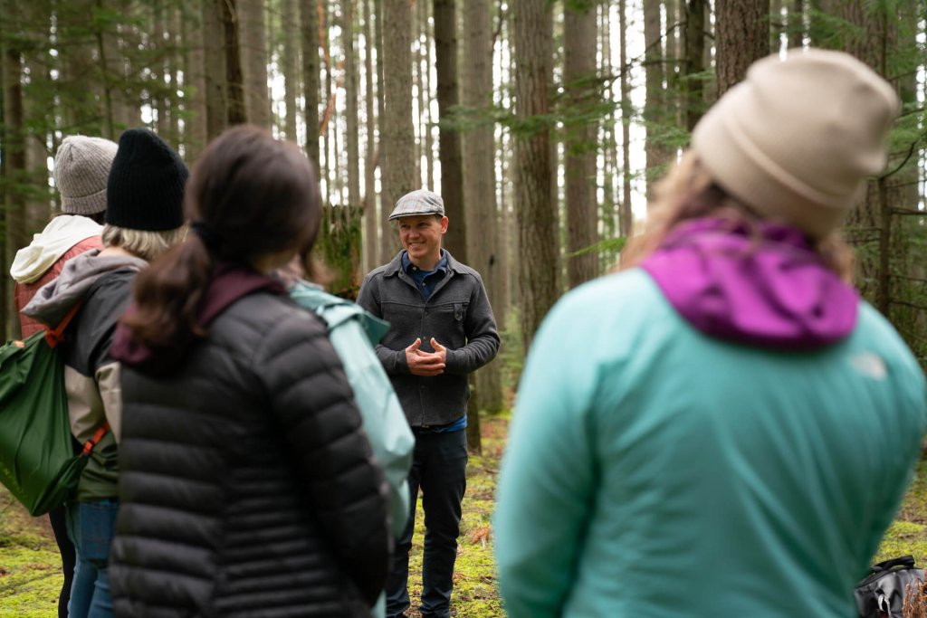 A group stands in forest during a forest bathing outing 