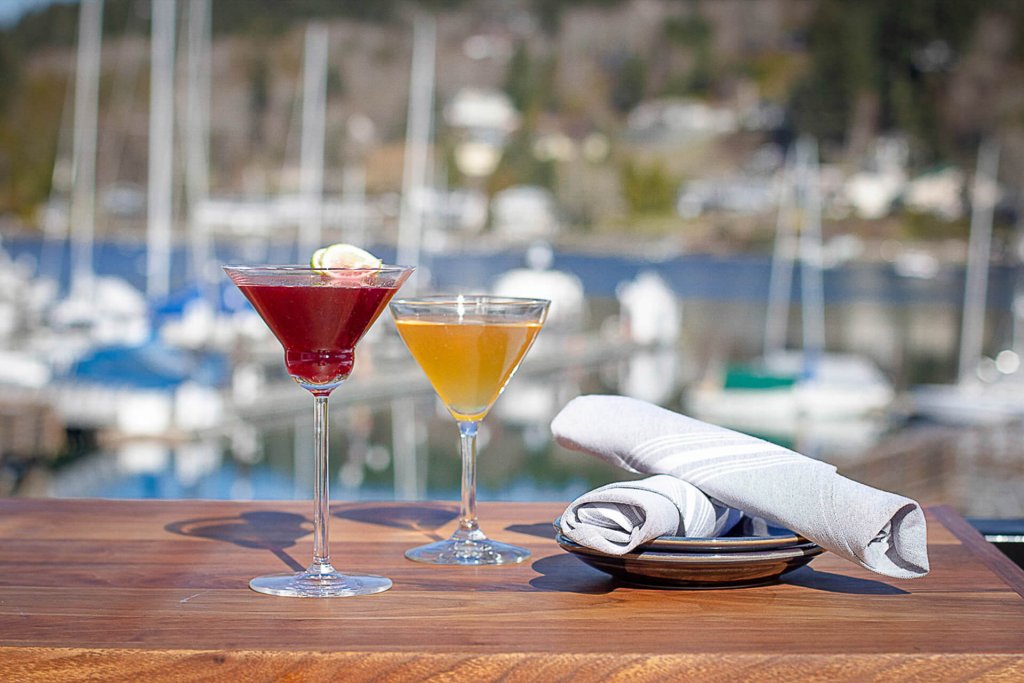 Bright cocktails in martini glasses on a wooden table outside at Brix25 in Gig Harbor.