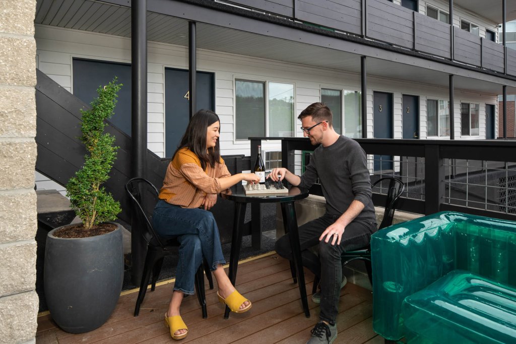 A man and woman play chess on a balcony at the Hotel McCoy