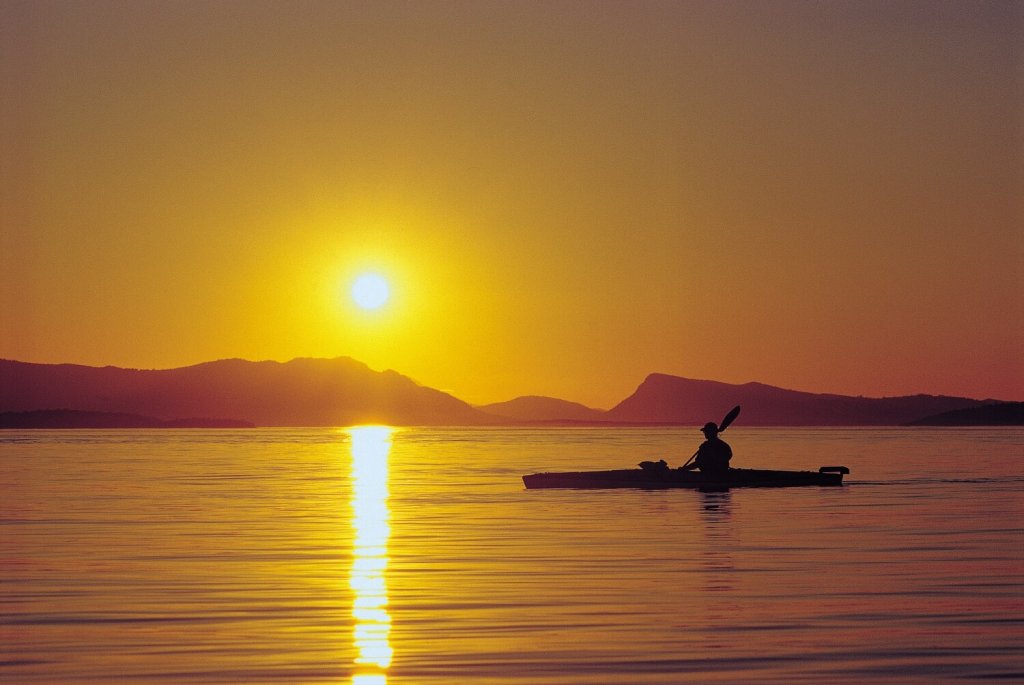 A kayaker is silhouetted at sunset in the San Juan Islands. 