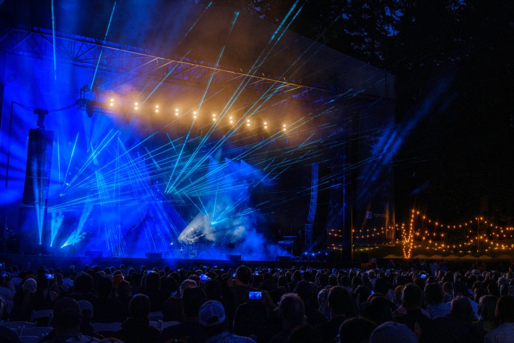 A photo taken at night of blue lights on a stage during a concert