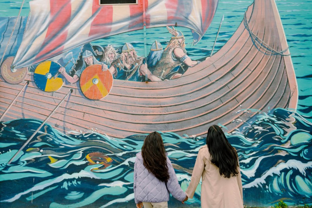 A photo of two women looking at a mural of a viking ship in Poulsbo