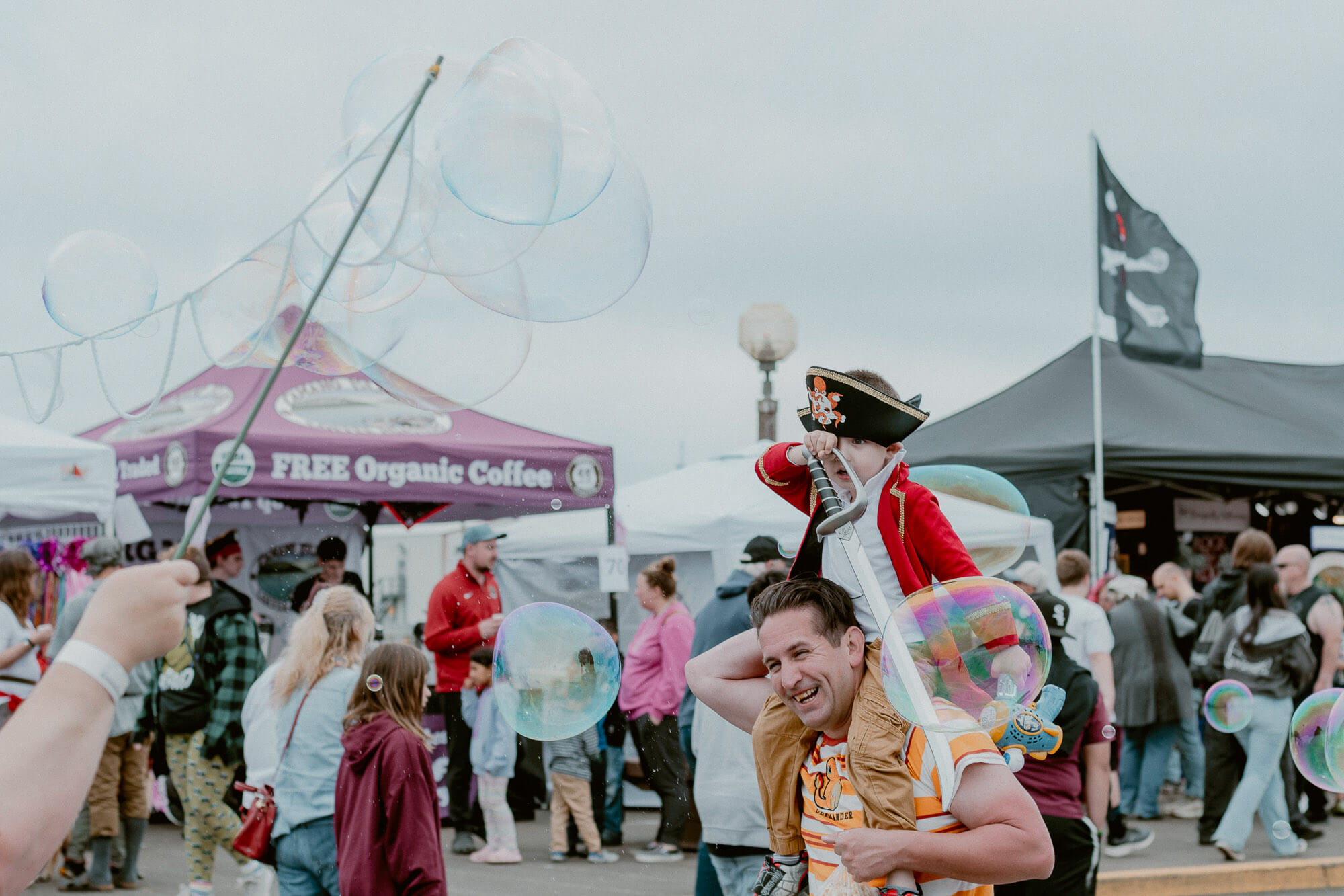 A child wearing a pirate hat sits on a man's shoulders during an event in Westport