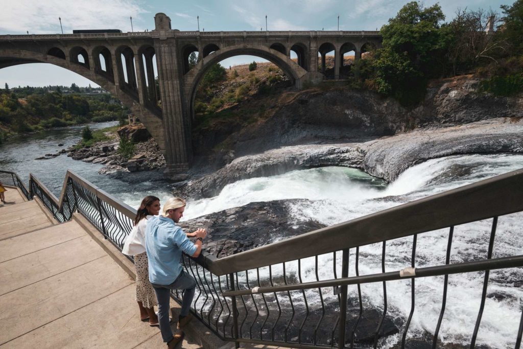 Man and woman leaning against railing looking out over Spokane Falls
