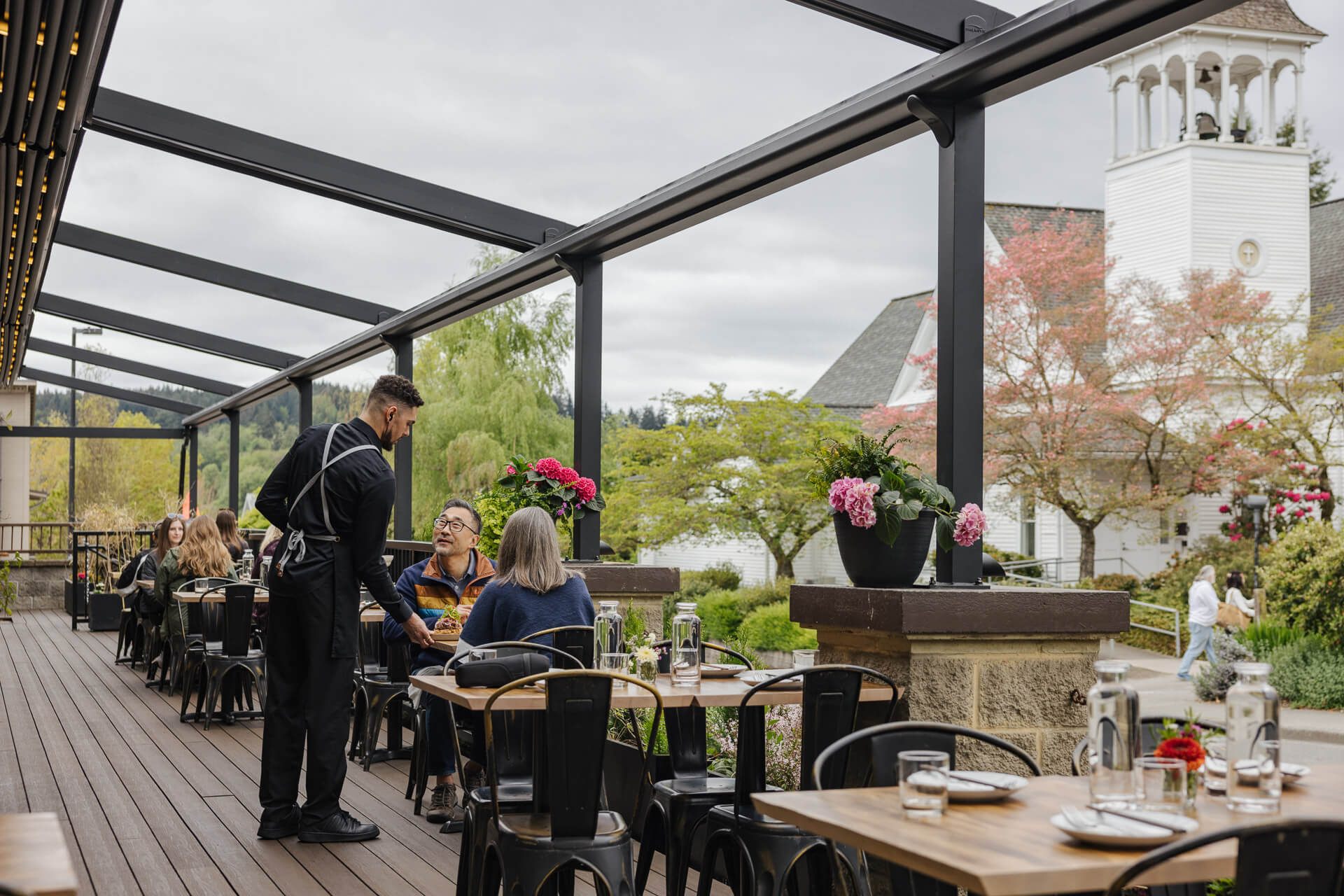A waiter serves a couple at an outside table at Ba Sa Restaurant