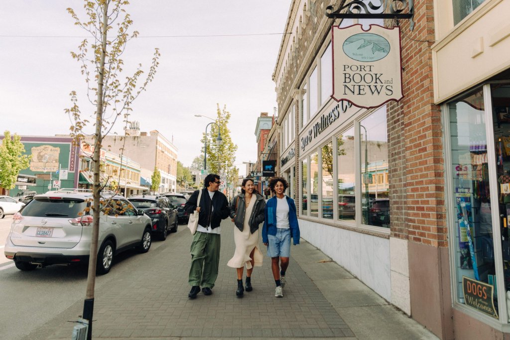 A group of three people walk along a street in downtown Port Angeles.
