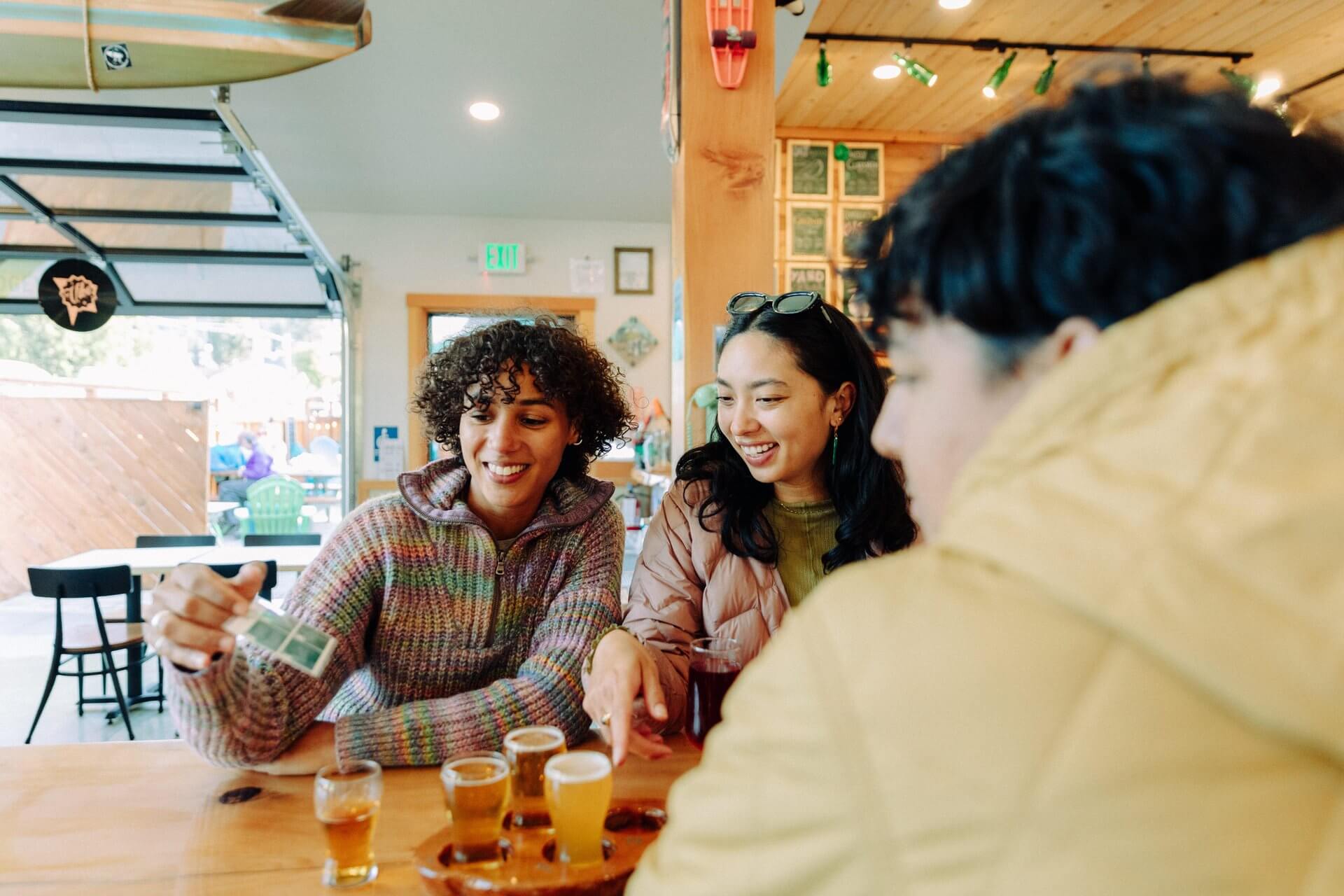 A group of people sit at a table with a flight of beer.
