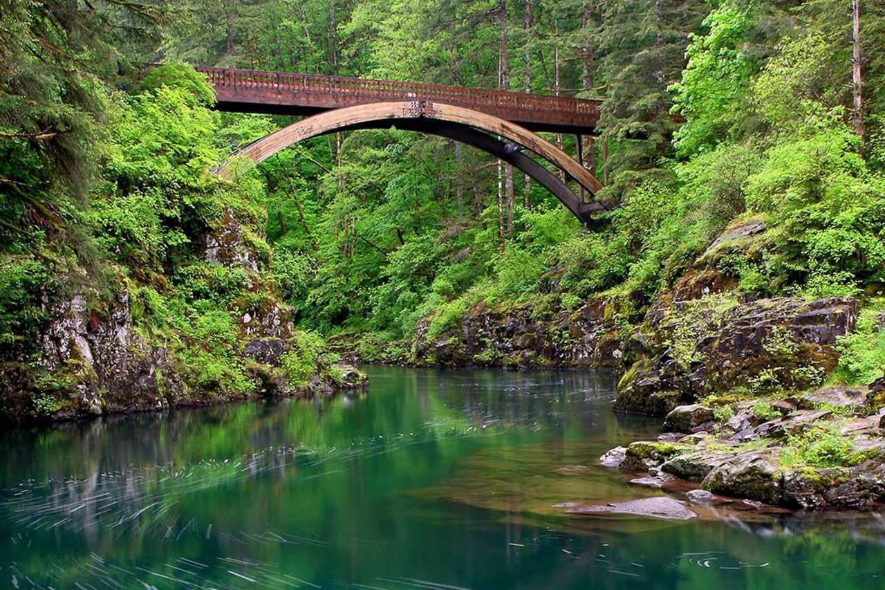 A rust-colored pedestrian bridge over Moulton Falls